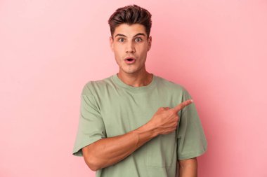 Pembe arka planda izole edilmiş genç beyaz adam yan tarafı gösteriyor.