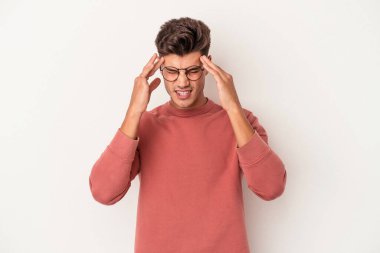 Beyaz arka planda izole olmuş genç beyaz bir adam başı ağrıyor, yüzüne dokunuyor..