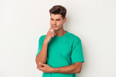 Beyaz arka planda izole edilmiş genç beyaz adam alaycı bir ifadeyle kameraya bakıyor..