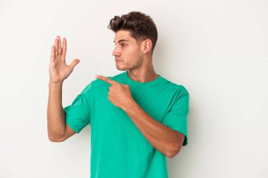Beyaz arka planda izole edilmiş genç beyaz bir adam gülümseyerek beş numarayı parmaklarıyla gösteriyor..