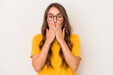 Beyaz arka planda izole edilmiş genç beyaz kadın elleriyle ağzını kapatırken şok oldu..