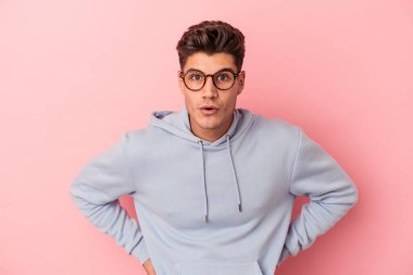 Pembe arka planda izole edilmiş genç beyaz adam gördüğü bir şey yüzünden şoka uğruyor..