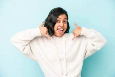 Mavi arka planda izole edilmiş genç Latin kadın parmakları olan bir cep telefonu hareketi gösteriyor..