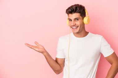 Pembe arka planda müzik dinleyen beyaz bir adam bir palmiye üzerinde fotokopi alanı ve belinde başka bir el tutarken görülüyor..