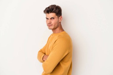 Beyaz arka planda izole edilmiş genç beyaz bir adam şüpheli, belirsiz, seni muayene ediyor..