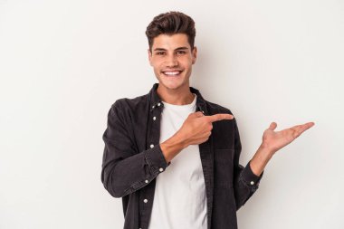 Beyaz arka planda izole edilmiş genç beyaz bir adam, palmiye üzerinde bir fotokopi alanı tutarken heyecanlı..