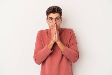 Beyaz arka planda izole edilmiş genç beyaz bir adam ağzı kapalı ve elleri endişeli görünüyor..