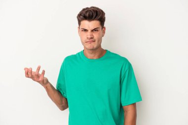 Beyaz arka planda izole edilmiş genç beyaz bir adam sorgulama sırasında omuz silkiyor ve şüphe duyuyor..