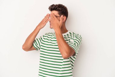 Beyaz arka planda izole edilmiş genç beyaz bir adam elleriyle gözlerini kapatmaktan korkuyor..