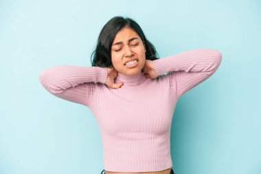 Mavi arka planda izole edilmiş genç Latin bir kadın sabit yaşam tarzından dolayı boyun ağrısı çekiyor..