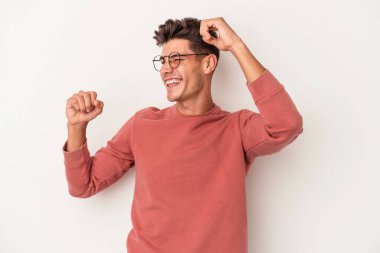 Beyaz arka planda izole genç beyaz adam özel bir günü kutluyor, atlıyor ve enerjiyle kollarını kaldırıyor..