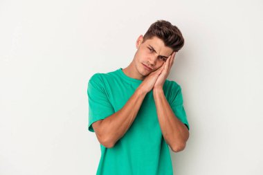 Beyaz arka planda izole edilmiş genç beyaz adam esniyor. Ağzı eliyle kapatan yorgun bir hareket sergiliyor..