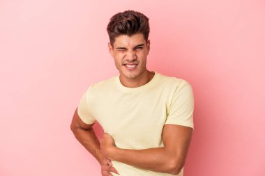 Pembe arka planda karaciğer ağrısı çeken, karnı ağrıyan genç beyaz bir adam..