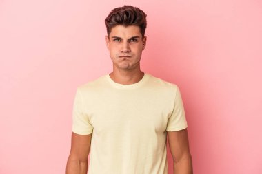 Pembe arka planda izole edilmiş genç beyaz adamın yanakları şişer, yorgun bir ifadesi vardır. Yüz ifadesi kavramı.