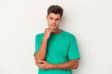 Beyaz arka planda izole edilmiş genç beyaz bir adam şüpheli, belirsiz, seni muayene ediyor..