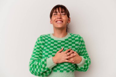 Arjantinli genç bir kadın beyaz arka planda izole halde gülüyor ellerini yüreğine koyuyor, mutluluk kavramını koruyor..