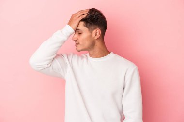Pembe arka planda izole edilmiş genç beyaz bir adam bir şeyi unutuyor. Alnına avuç içi ve gözlerini kapatarak vuruyor..