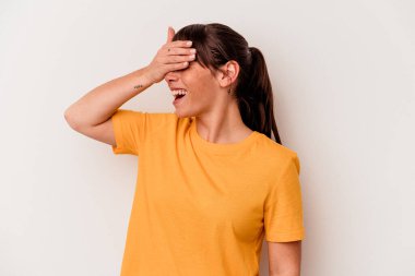 Beyaz arka planda izole edilmiş genç Arjantinli kadın elleriyle gözlerini kapatıyor, geniş bir gülümsemeyle bir sürpriz bekliyor..