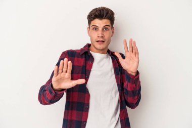 Beyaz arka planda izole genç beyaz adam yakın bir tehlike nedeniyle şoka uğruyor