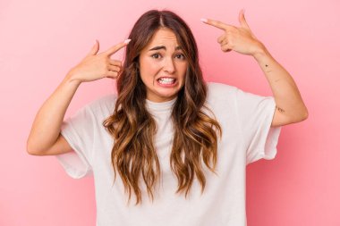 Pembe arka planda izole edilmiş beyaz bir kadın işaret parmağıyla hayal kırıklığı jesti gösteriyor..