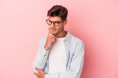 Pembe arka planda izole edilmiş genç beyaz adam bir strateji planlıyor, bir iş yolu düşünüyor..