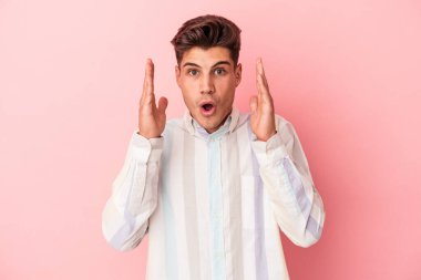 Pembe arka planda izole edilmiş genç beyaz adam şaşırdı ve şok oldu..