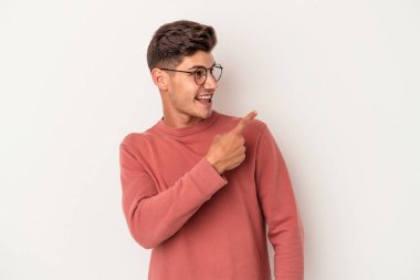 Beyaz arka planda izole edilmiş genç beyaz adam gülümseyen, neşeli ve keyifli bir tarafa bakıyor..