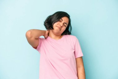 Mavi arka planda izole edilmiş genç Latin kadın stresten dolayı boynu ağrıyor, masaj yapıyor ve elle dokunuyor..