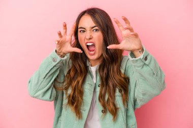 Pembe arka planda izole edilmiş genç beyaz kadın gergin elleriyle çığlık atıyor..