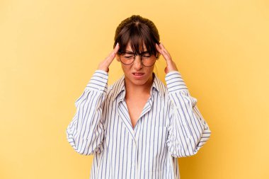 Sarı arka planda izole edilmiş genç Arjantinli kadın tapınaklara dokunuyor ve baş ağrısı çekiyor..