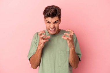 Pembe arka planda izole edilmiş genç beyaz adam gergin elleriyle çığlık atıyor..