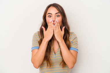 Beyaz arka planda izole edilmiş genç beyaz kadın elleriyle ağzını kapatırken şok oldu..
