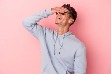 Pembe arka planda izole edilmiş genç beyaz adam ellerini başının üstünde tutarak neşeyle gülüyor. Mutluluk kavramı.