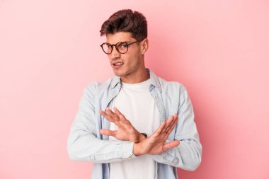 Pembe arka planda izole edilmiş genç beyaz adam inkar jesti yapıyor.