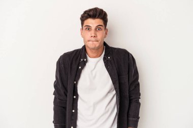 Beyaz arka planda izole edilmiş genç beyaz bir adam omuz silkiyor ve gözleri açık..