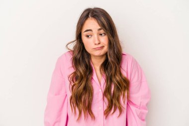 Beyaz arka planda izole edilmiş genç beyaz kadın omuzlarını silker ve gözleri açık kalır..