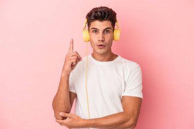 Pembe arka planda izole edilmiş müzik dinleyen beyaz bir adamın harika bir fikri var, yaratıcılık kavramı..