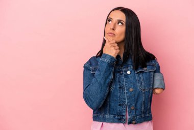 Pembe arka planda tek kollu beyaz bir kadın şüpheli ve şüpheci bir ifadeyle yana bakıyor..