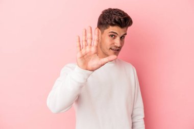 Pembe arka planda izole edilmiş genç beyaz bir adam tiksinti belirtisi gösteren birini reddediyor..