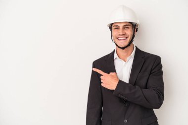 Beyaz arka planda izole edilmiş genç bir mimar gülümseyip, boş alanda bir şeyler gösteriyor..