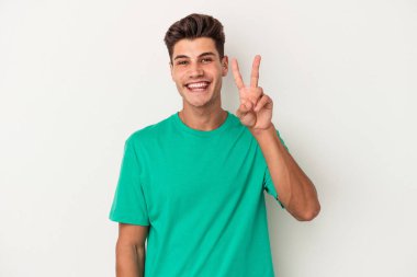 Beyaz arka planda izole edilmiş genç beyaz adam iki numarayı parmaklarıyla gösteriyor..