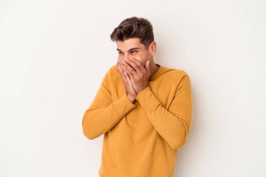 Beyaz arka planda izole olmuş genç beyaz bir adam bir şeye gülüyor, ağızlarını ellerle kapatıyor..