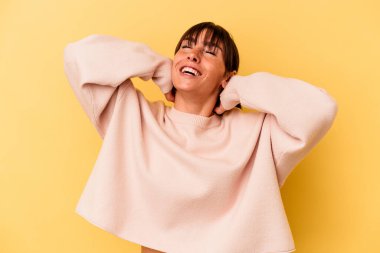 Arjantinli genç bir kadın sarı arka planda izole edilmiş, kendinden emin, elleri başının arkasında..