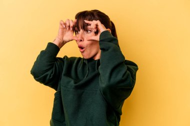 Sarı arka planda izole edilmiş genç Arjantinli kadın bir başarı fırsatı bulmak için gözlerini açık tutuyor..