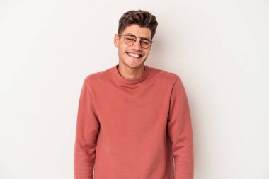 Beyaz arka planda izole edilmiş genç beyaz adam gülüyor ve gözlerini kapıyor, rahatlamış ve mutlu hissediyor..