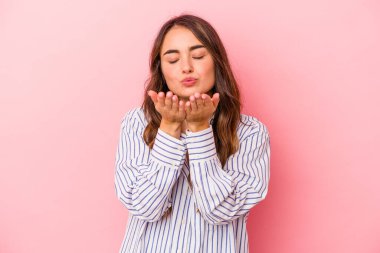 Beyaz bir kadın pembe arka planda izole edilmiş dudaklar kıvrılmış ve hava öpücüğü göndermek için avuç içleri tutulmuş..