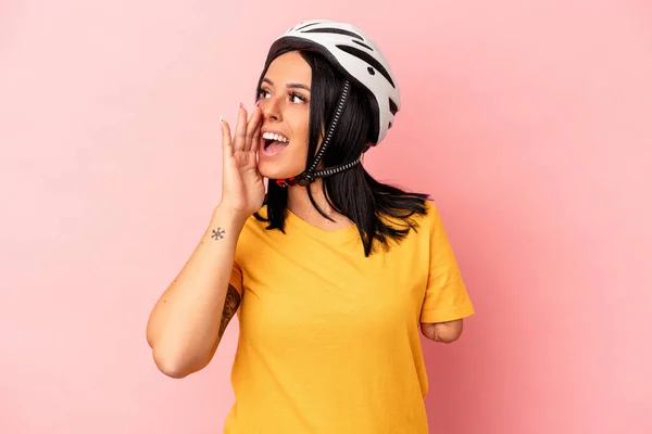 ピンクの背景の叫びに隔離された自転車のヘルメットを身に着けている一本の腕を持つ若い白人女性と近くに手のひらを保持口を開けた — ストック写真