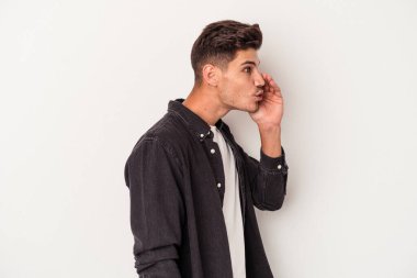 Beyaz arka planda izole edilmiş genç beyaz bir adam gizli bir sıcak fren haberi veriyor ve yana bakıyor.