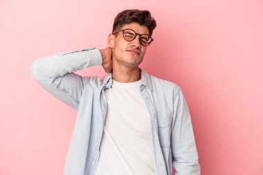 Genç beyaz adam pembe arka planda izole edilmiş dirsek masajı yapıyor, kötü bir hareketin ardından acı çekiyor..