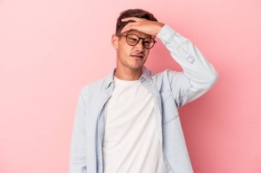 Pembe arka planda izole edilmiş genç beyaz adam tapınaklara dokunuyor ve baş ağrısı çekiyor..